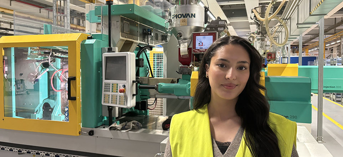 Junge lächelnde Person mit gelber Warnweste in der Produktionshalle Junge lächelnde Person mit gelber Warnweste in der Produktionshalle