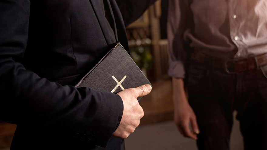 Bibel in der Hand eines Pfarrers. Bild von Freepik.